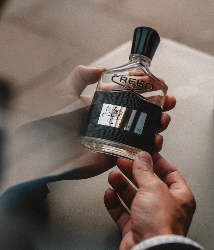 Hands inspecting Creed Aventus bottle 