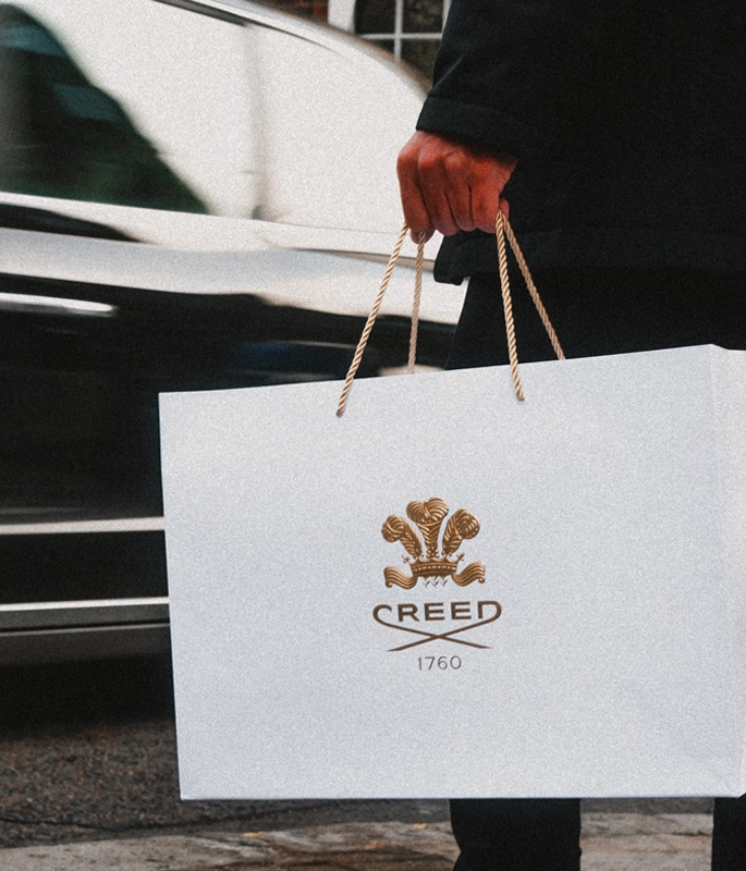 Creed shopping bag held by man's hands in cit
